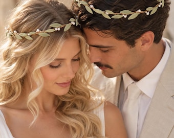 May include: A pair of matching headbands featuring a thin, flexible vine-like base adorned with small, light green fabric leaves and tiny white pearl accents. The headbands are designed to be worn as a crown, encircling the head with a delicate, botanical-inspired arrangement of foliage and pearls.