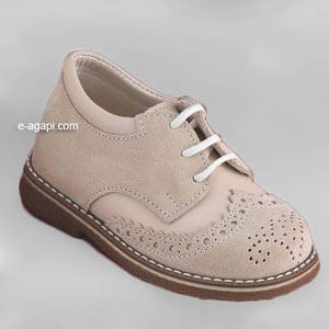 May include: Beige suede leather oxford shoes with white laces and a decorative wingtip design. The shoes have a brown rubber sole.