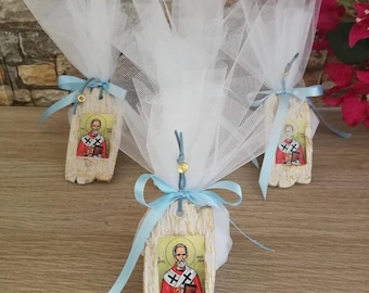 May include: Three small white wooden tags with a blue ribbon and white tulle. Each tag features a colorful image of Saint Nicholas, a religious icon.