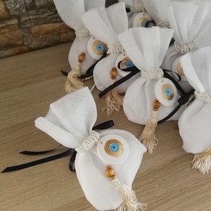Bomboniere appese con malocchio, sacchetti bianchi, regali per gli ospiti, bomboniere greche, koufeta per il battesimo, souvenir per il battesimo di neonati e bambine