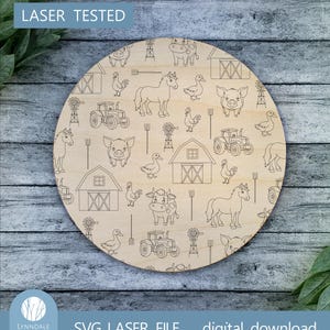 Peut inclure: Un design de ferme en noir et blanc découpé au laser avec des animaux, des granges et des tracteurs. Le motif est sur un morceau de bois rond. Le texte "LASER TESTED" est en haut de l'image.