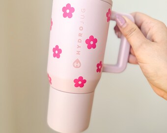 Könnte beinhalten: Eine rosafarbene Edelstahl-Reise-Thermoskanne mit Blumenmuster und dem Text "HYDROJUG" an der Seite.