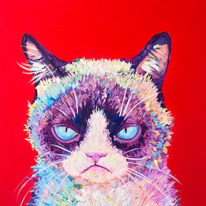 May include: A colorful painting of a grumpy cat with blue eyes. The cat is painted in a variety of colors, including purple, pink, blue, and green. The background is a solid red.