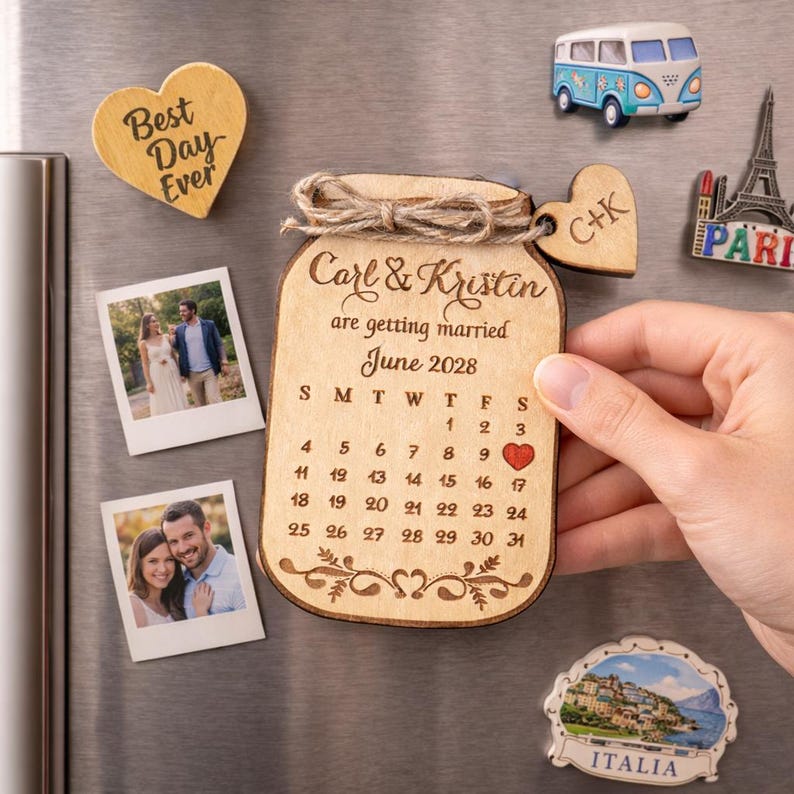 May include: Wooden wedding calendar magnet in the shape of a jar, with the names "Carl & Kristin" and the date "June 2028." Other magnets include a heart with "Best Day Ever," photos, a heart with initials, a van, the Eiffel Tower, and an Italian scene.