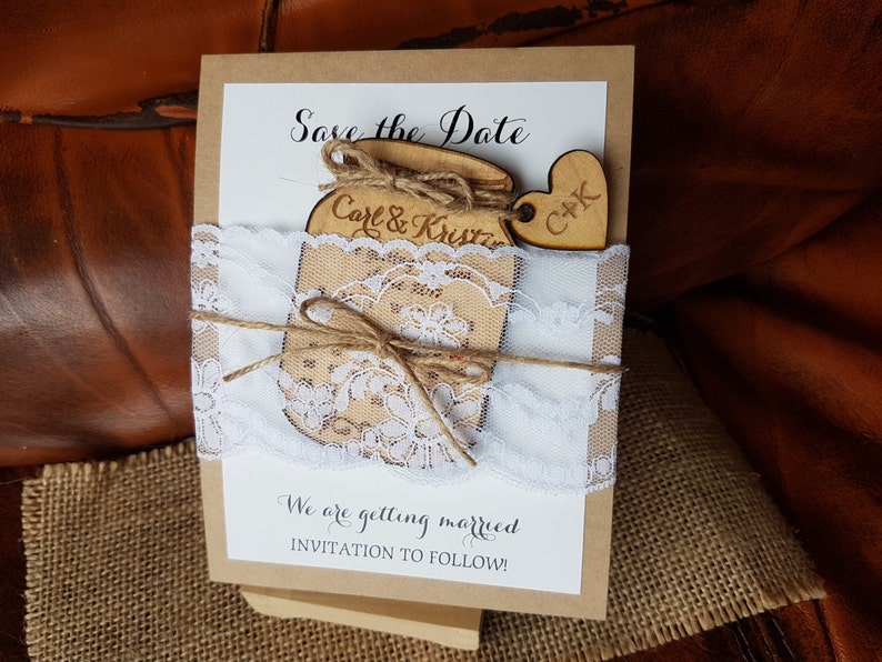 May include: A rustic wedding invitation with a wooden jar and heart embellishments. The invitation features the text "Save the Date" and "Carl & Kristin". It is decorated with white lace and twine, with the text "We are getting married, INVITATION TO FOLLOW!"