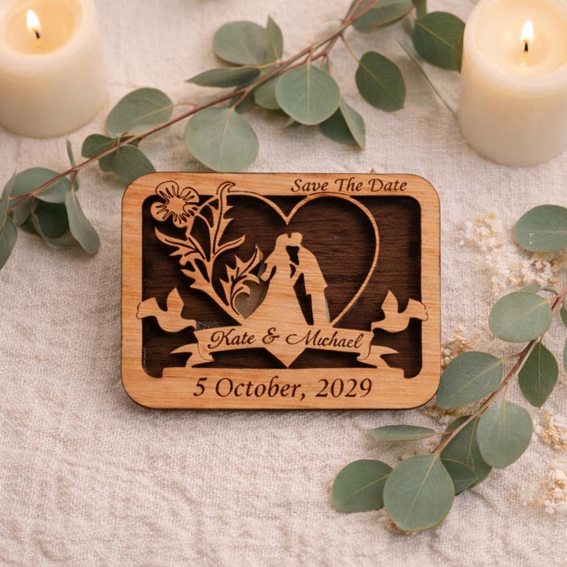 May include: Wooden rectangular save-the-date magnet with a heart-shaped cutout featuring a kissing couple silhouette. The magnet includes the names "Kate & Michael" and the date "5 October, 2029".