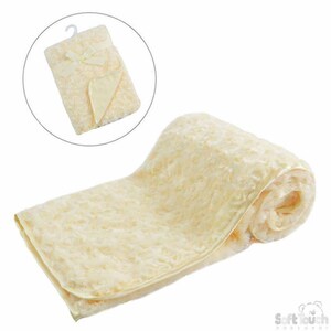 May include: A soft, cream-coloured baby blanket with a satin trim. The blanket is rolled up and has a small bow on the top.