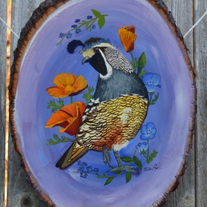May include: A hand-painted wooden slice with a purple background features a detailed painting of a quail with orange and yellow flowers and blue forget-me-nots. The artist's signature is visible in the lower right corner.