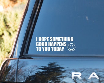 May include: A white vinyl decal on a black vehicle's rear window. The decal reads "I HOPE SOMETHING GOOD HAPPENS TO YOU TODAY" with a smiling face graphic. The vehicle's brand name, "RANG", is visible.