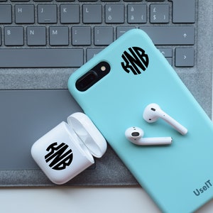 May include: A light blue phone case with a white monogram sticker on the back. The case is on a gray keyboard with white wireless earbuds next to it. The phone case has the text "UselT" printed on the bottom right corner.