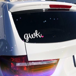 Pode incluir: Carro branco com um vidro traseiro preto. O vidro tem um adesivo de vinil branco que diz "geek" com um cora&ccedil;&atilde;o rosa.