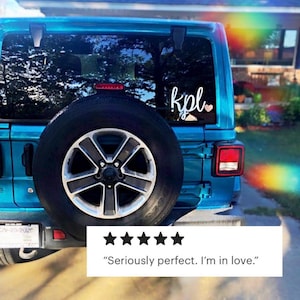 Pode incluir: Um Jeep azul com um adesivo de vinil branco na janela traseira que diz "kpl" com um pequeno cora&ccedil;&atilde;o rosa. O adesivo est&aacute; na janela traseira do carro.