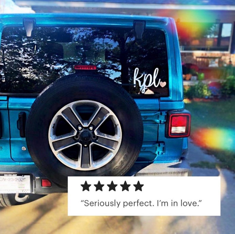 Pode incluir: Um Jeep azul com um adesivo de vinil branco na janela traseira que diz "kpl" com um pequeno cora&ccedil;&atilde;o rosa. O adesivo est&aacute; na janela traseira do carro.