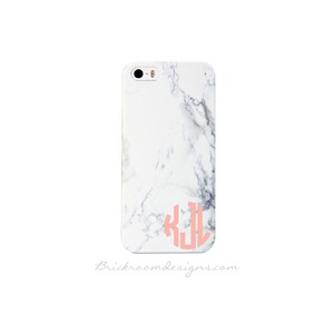 May include: White iPhone case with a marble pattern and a pink monogram "KJL" on the back.