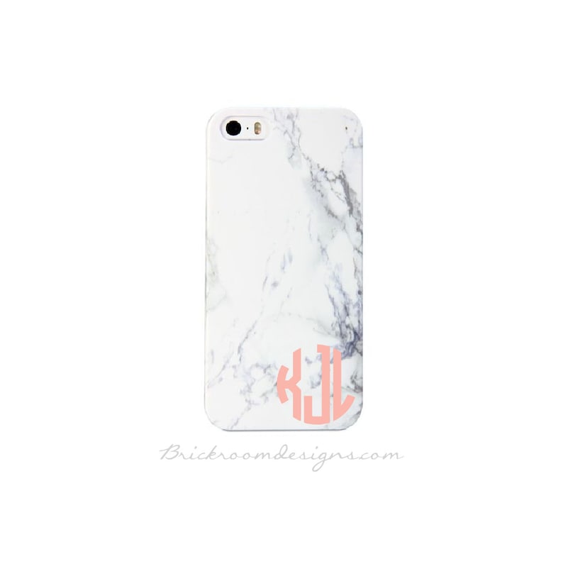 May include: White iPhone case with a marble pattern and a pink monogram "KJL" on the back.