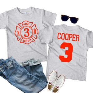 May include: Two gray t-shirts with red text. One shirt has a fire department logo with the number 3. The other shirt has the name "COOPER" and the number 3.