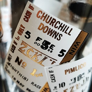 May include: A white ticket with gold lettering for the Churchill Downs race. The ticket is numbered 5 and is for the eighth race on May 16th. The ticket is for the ZCKI horse and is a win ticket.