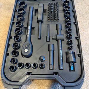 Op de afbeelding: Een zwarte gereedschapsset in een gegoten kunststof koffer, voorzien van een ratel, verlengstukken en diverse doppen. De gereedschappen zijn gelabeld met ELEAD CR-V en bevatten een verlengstuk van 6 inch.
