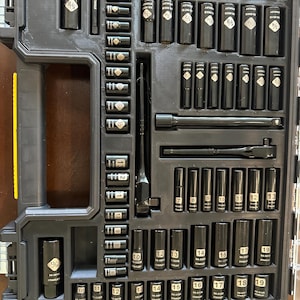 May include: A black Stanley socket set in a black plastic case. The set includes various sockets, a ratchet, and extensions. The sockets are labeled with sizes in inches, ranging from 3/8 to 3/4. The case is open, revealing the organized arrangement of tools.