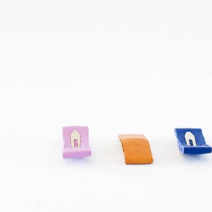 May include: Three leather tags with metal clasps. The tags are pink, orange, and blue.