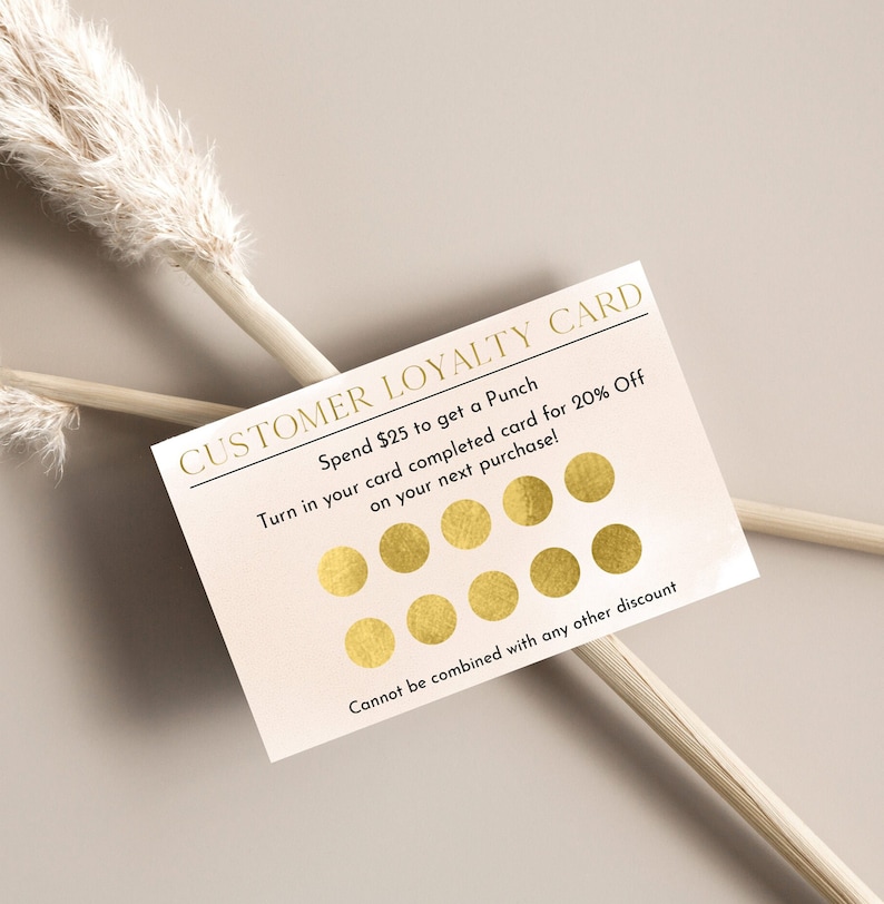 May include: A white loyalty card with gold text and circles. The text reads "CUSTOMER LOYALTY CARD" and "Spend $25 to get a Punch. Turn in your card completed card for 20% Off on your next purchase! Cannot be combined with any other discount."