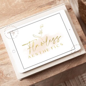 May include: A white tablet screen displaying a gold logo with the text "Flawless Aesthetics" and a line drawing of a face. The logo is on a light brown watercolor background.