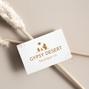 May include: A white business card with a logo of a desert scene with a sun and three cacti in brown. The text "GYPSY DESERT boutique co." is printed in brown below the logo.