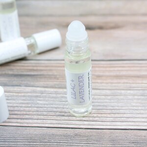 May include: A clear glass roller bottle with a white cap and label. The label reads "Lilac + Lavender Natural Perfume Oil".