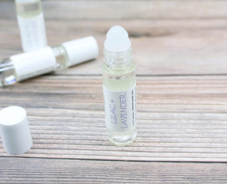 May include: A clear glass roller bottle with a white cap and label. The label reads "Lilac + Lavender Natural Perfume Oil".