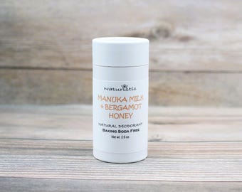 Può includere: Stick di deodorante bianco con un'etichetta che recita "Naturistic Manuka Milk + Bergamot Honey Natural Deodorant Baking Soda Free Net wt. 2.6 oz."