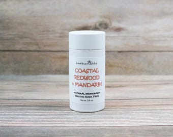 May include: White deodorant stick with the text "Naturistic Coastal Redwood + Mandarin Natural Deodorant Baking Soda Free Net Wt. 2.6 oz."