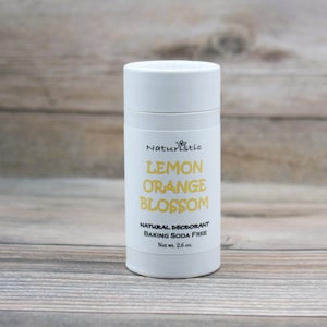 May include: White deodorant stick with a yellow label that reads "Naturistc Lemon Orange Blossom Natural Deodorant Baking Soda Free Net wt. 2.6 oz."