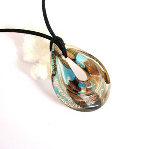 May include: A teardrop-shaped pendant necklace with a black cord. The pendant is made of glass with layers of brown, gold, and blue colours.