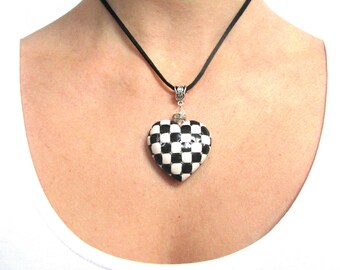 May include: A black and white chequered heart pendant necklace with a silver chain and a black cord.