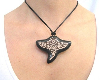 May include: A black pendant necklace with a detailed carving of a manta ray. The pendant is made of wood and has a black cord.