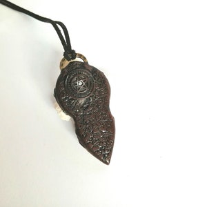 May include: A brown pendant necklace with a pentagram design. The pendant is shaped like a teardrop and has a textured surface.