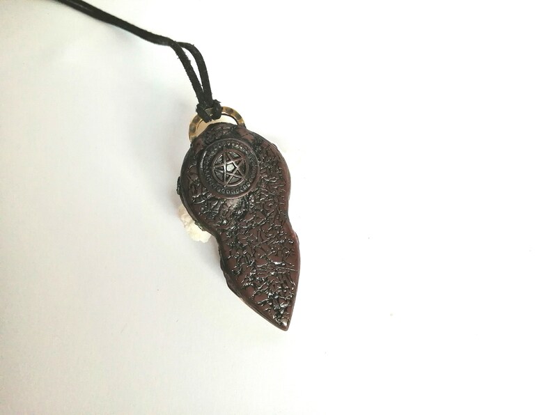 May include: A brown pendant necklace with a pentagram design. The pendant is shaped like a teardrop and has a textured surface.