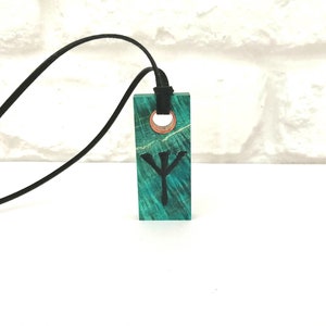 May include: A green wooden pendant with a black Yggdrasil symbol, hanging from a black leather cord.