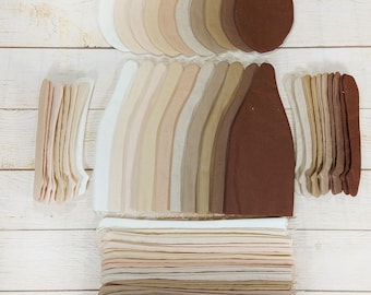 May include: A collection of fabric scraps in various shades of brown, beige, and white, arranged in a pattern on a white wooden surface. The fabric pieces are cut into different shapes, including circles, ovals, and rectangles.