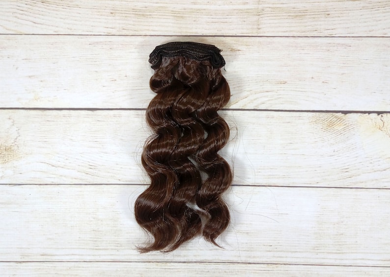 Puede incluir: Una extensi&oacute;n de cabello ondulado marr&oacute;n con un clip de sujeci&oacute;n.