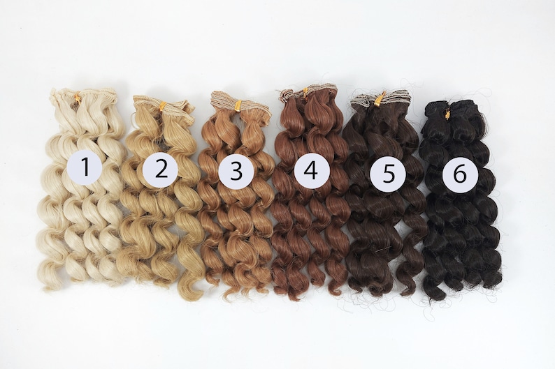 May include: Six wefts of curly doll hair in various shades of blonde, brown, and black. The wefts are numbered 1 through 6.