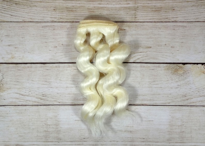 Puede incluir: Una trama de extensiones de cabello humano ondulado, rubio platino.