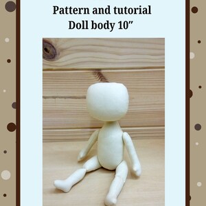 May include: PDF pattern and tutorial for a 10 inch doll body. The doll body is made of white fabric and is sitting on a wooden surface.