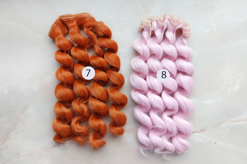 May include: Two sets of curly hair extensions for dolls. One set is orange and the other is pink. The sets are labeled with numbers 7 and 8.