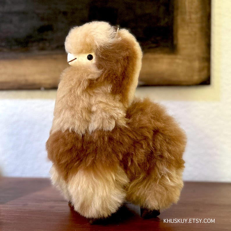 Op de afbeelding: Een bruin en cr&egrave;mekleurig alpaca knuffeldier. Het speelgoed is gemaakt van zacht, pluche alpaca-haar en heeft een schattig, realistisch gezicht.