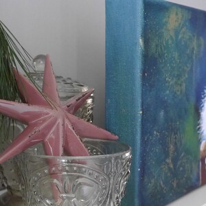 K&ouml;nnte beinhalten: Eine dekorative Anordnung mit einem rosa Sternornament, Glasflaschen und einem kleinen Gem&auml;lde eines Nussknackers. Der Stern befindet sich in einer dekorativen Glasschale. Ein Zweig Gr&uuml;n f&uuml;gt der Pr&auml;sentation eine nat&uuml;rliche Note hinzu.