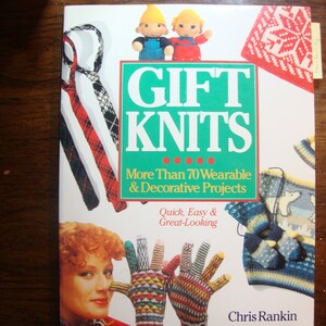 May include: A book titled "GIFT KNITS" with a green and white cover. The cover features images of knitted items, including ties, gloves, and a sweater. The text reads "More Than 70 Wearable & Decorative Projects".