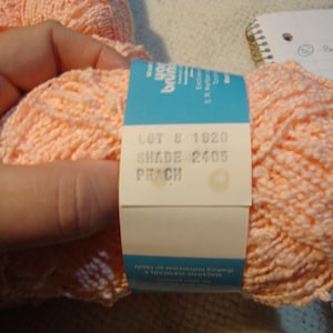 May include: A skein of peach-colored yarn with a label that reads "LOT 8 1920 SHADE 2405 PEACH".