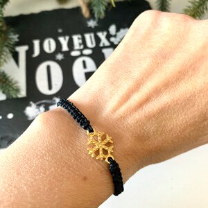 May include: A black braided bracelet with a gold snowflake charm.