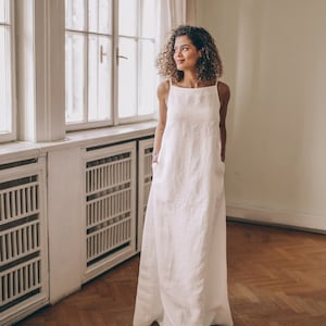 Designed entirely in natural linen, this floor length sleeveless dress is a seasonal essential. А minimalist piece that has elongated silhouette, hem pockets, boat neckline and a tie knot closure at the back.